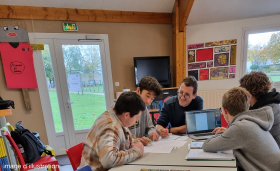 Adolescents en train de travailler regroupés autour d'un ordinateur