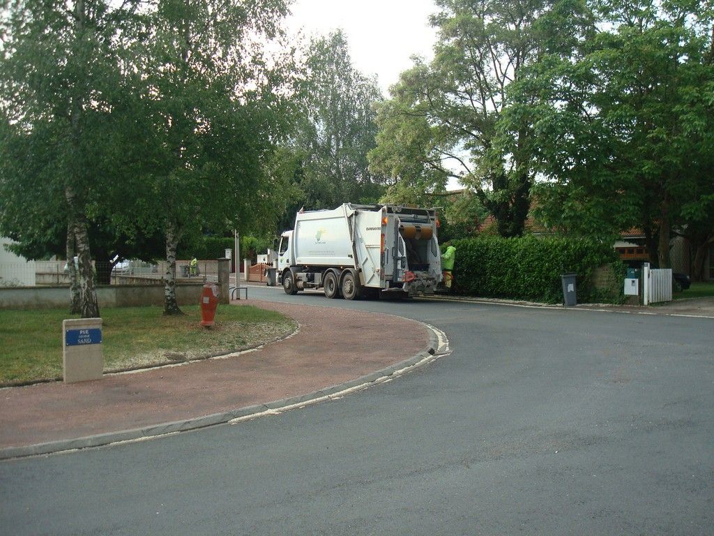 camion de collecte des déchets ménager en cours de collecte dans la rue Saint Exupéry