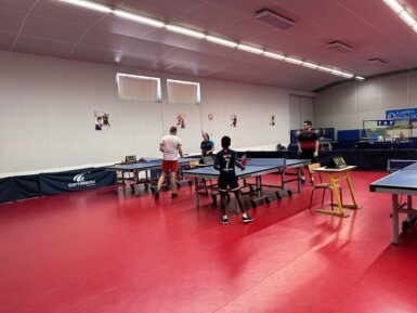 Joueurs de tennis de table pratiquant dans une salle.