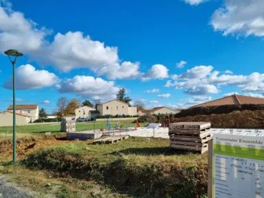 Au premier plan un permis de construire. Au second plan une maison en construction dans un lotissement