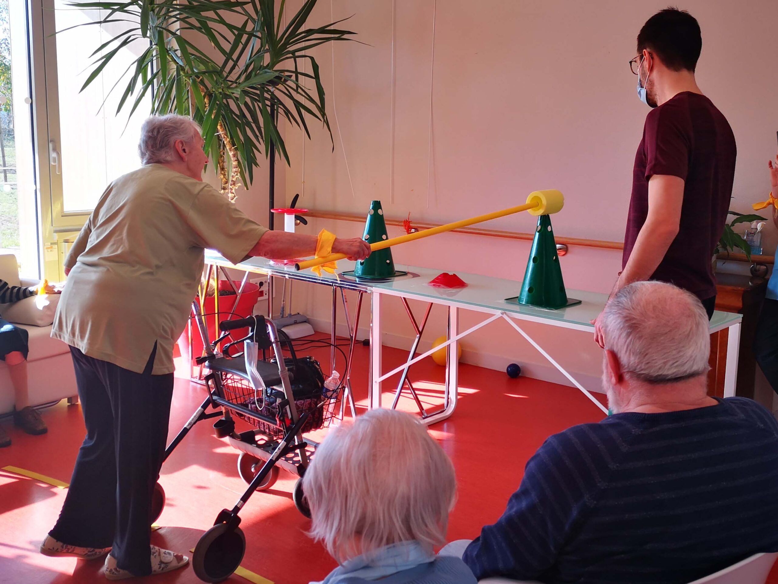 Une résidente de l'Ehpad lors d'une activité physique pratiquée avec une perche et des cônes
