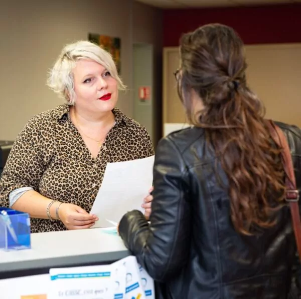 1 personne de l'accueil féminine de l'appui écoute et donne des documents à une autre personne féminine