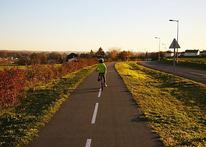 Enfant roulant à vélo sur une piste cyclable au coucher du soleil