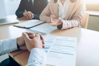 Main croisées devant un CV posé sur la table avec deux personnes en face
