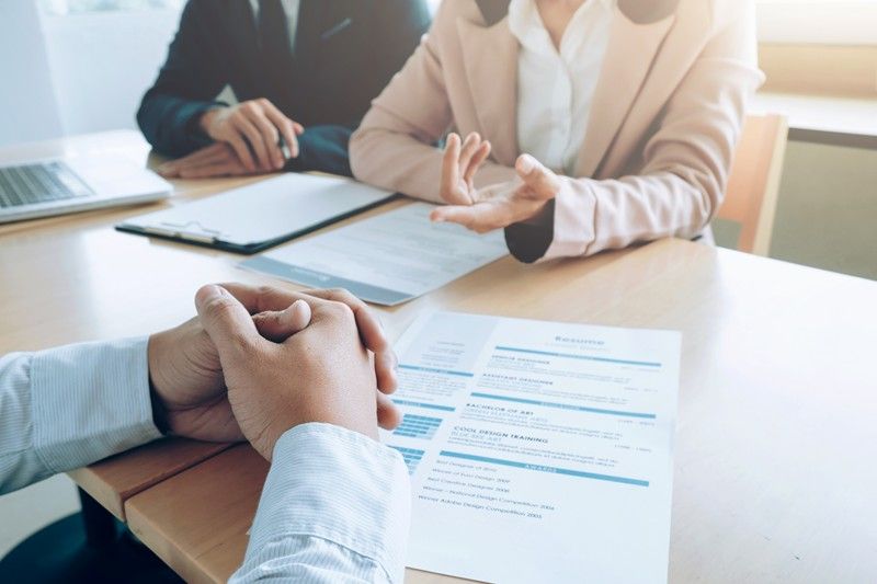Main croisées devant un CV posé sur la table avec deux personnes en face