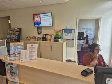 Agent d'accueil au téléphone derrière le guichet du bureau de la vie associative dans la mairie de Jaunay-Marigny.