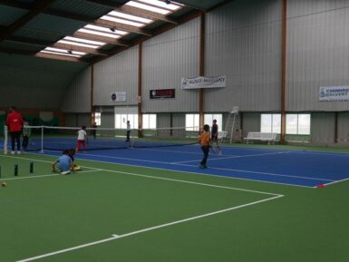Enfants jouant au tennis sur des courts couverts