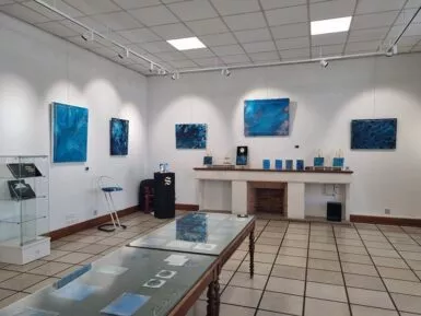 Salle d'exposition avec tableaux grand format dans les tons de bleu