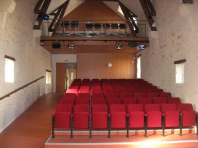Salle de spectacle avec des fauteuils rouges et un balcon