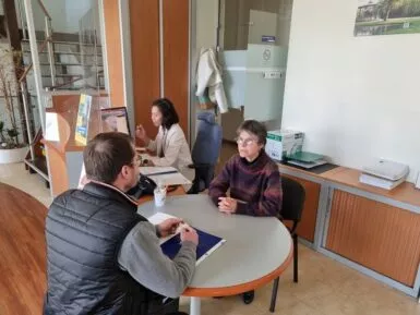 Un administré à l'accueil de la Mairie reçu par deux agents au comptoir