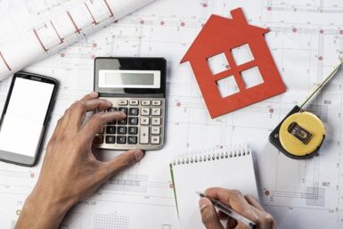Plan de maison avec une calculatrice, un carnet et un mètre mesureur
