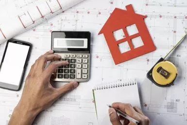 Plan de maison avec une calculatrice, un carnet et un mètre mesureur