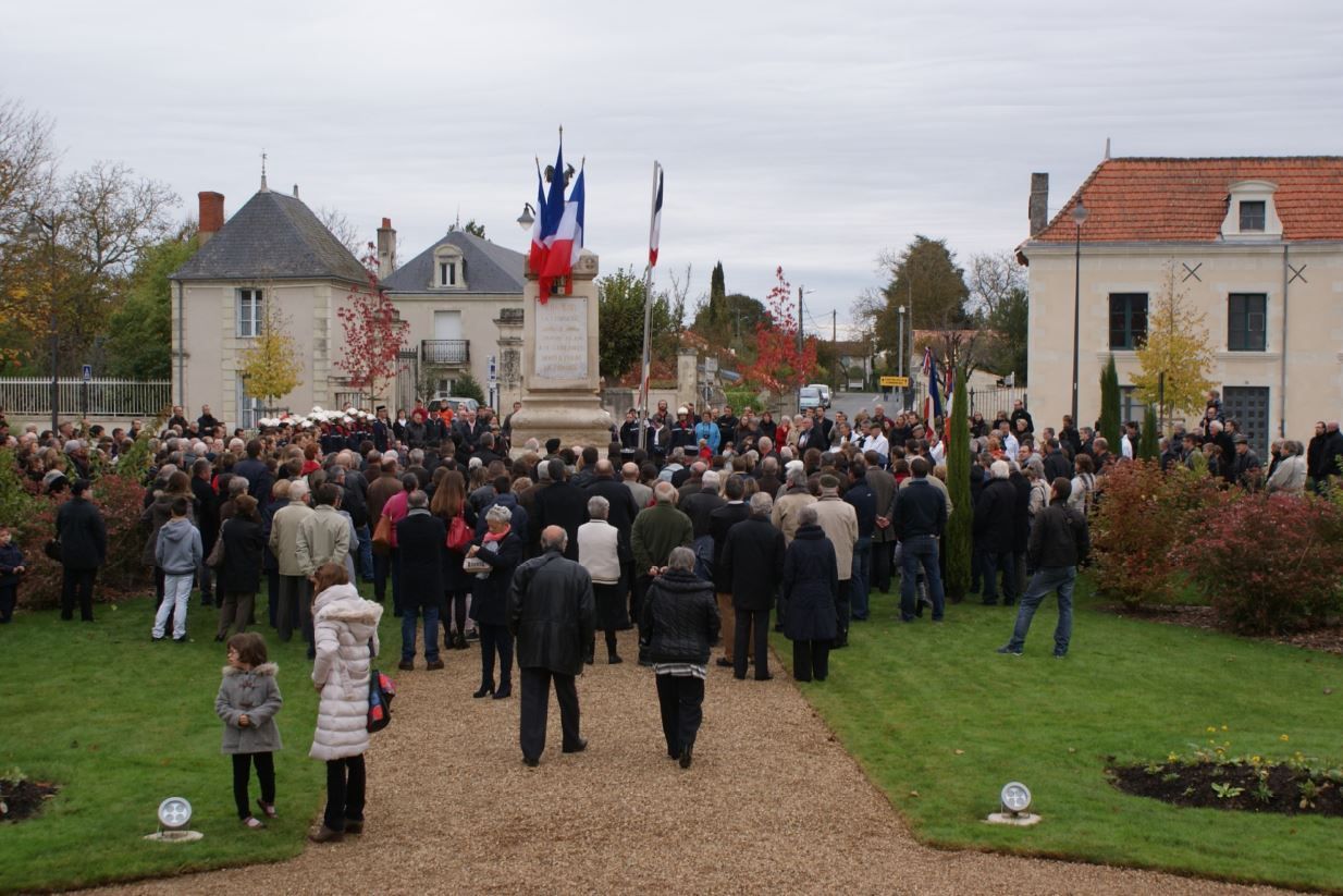 Foule regroupée autour du monument aux Morts paré des drapeaux tricolores à l'occasion d'une cérémonie du 11 novembre devant la Mairie de Jaunay-Marigny.