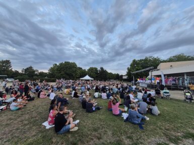 public assis devant la scène installée sur le parvis de l'agora un soir d'été