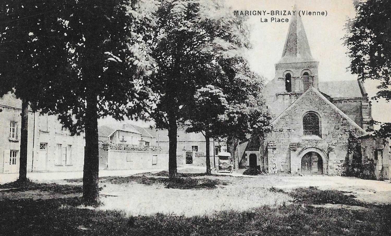 Carte postale en noir et blanc représentant la place Elie Fournier, ses arbres et en arrière-plan l'église à côté de laquelle est stationnée une automobile du début du 20ème siècle.