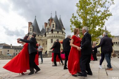 Couples de danseurs en costume et robe de soirée dansant une valse sur le parvis du château de Dissay