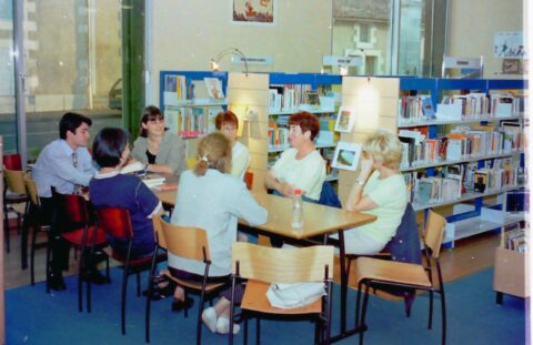 Photo du début des années 2000 à la bibliothèque où une dizaine de personnes sont autour d'une table pour partager leurs coups de cœur littéraire.