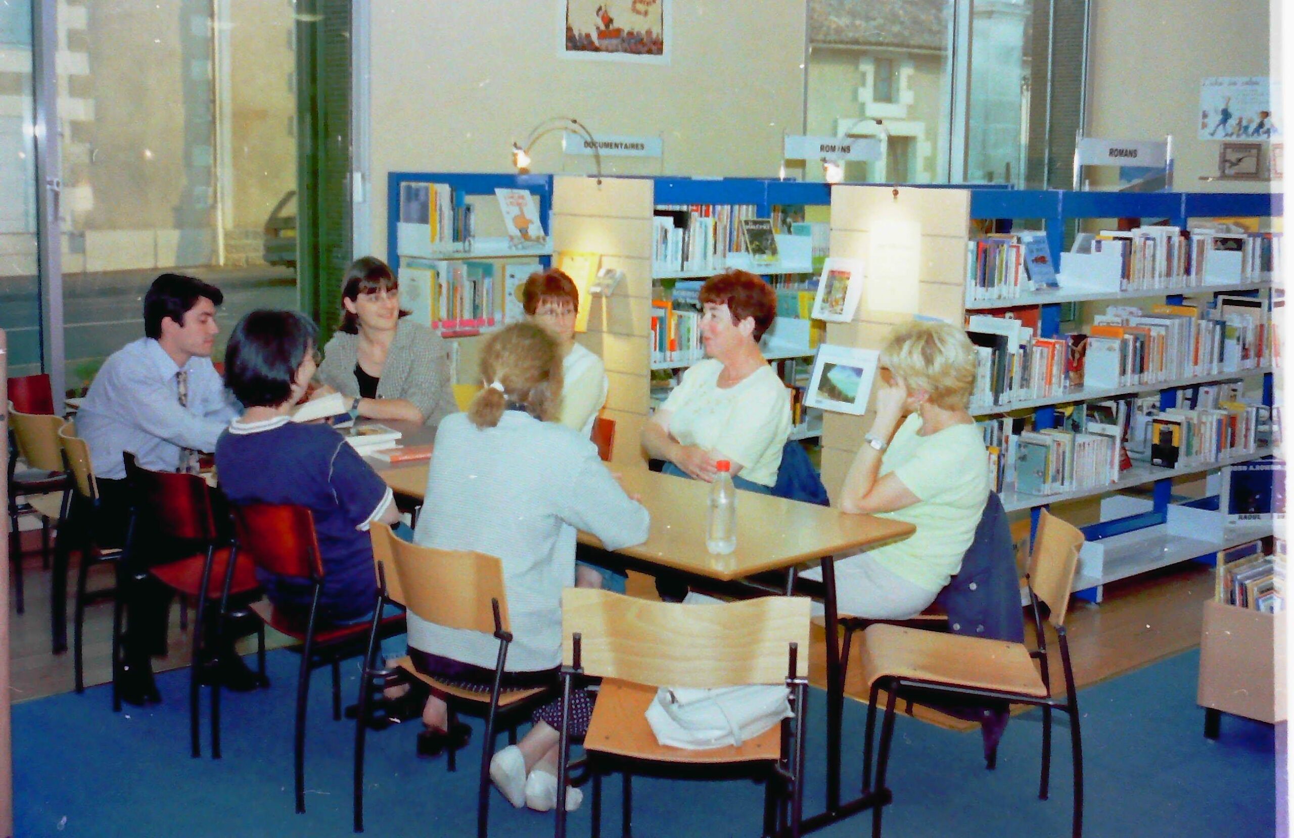 Photo du début des années 2000 à la bibliothèque où une dizaine de personnes sont autour d'une table pour partager leurs coups de cœur littéraire.