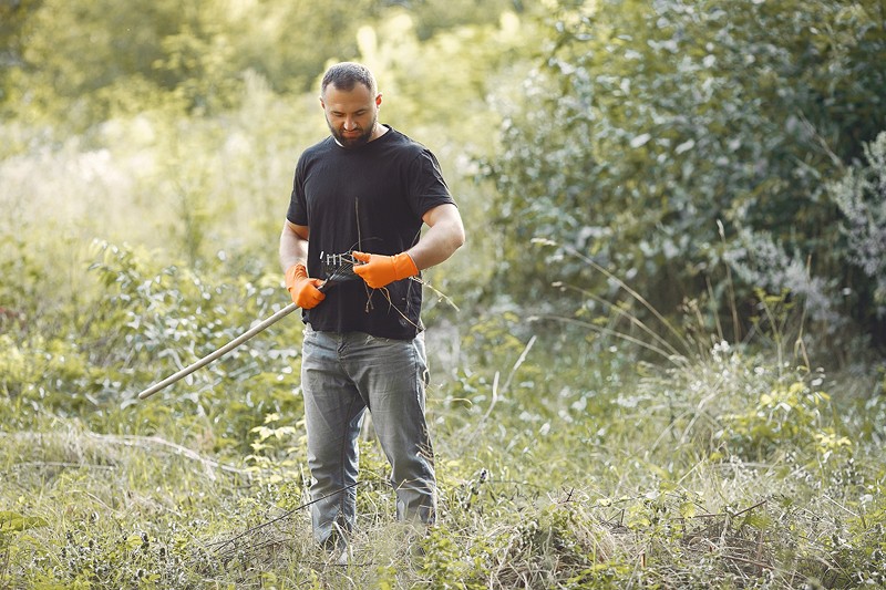 Homme avec un râteau à feuille dans la nature