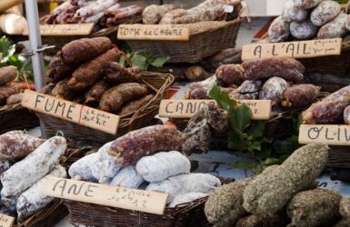 présentation de différentes sortes de saucissons secs sur un étal de marché.