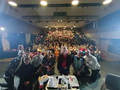 comédiens au premier plan sur la scène avec en arrière plan le public assis dans les gradins