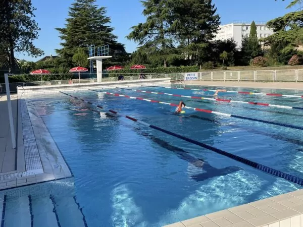 Piscine de Jaunay-Marigny avec des nageurs dans les lignes d'eau. A l'arrière plan des parasols avec des jury qui comptent les longeurs