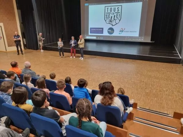 Enfants assis dans les gradins de l'Agora face au grand écran sur lequel est diffusé le logo 