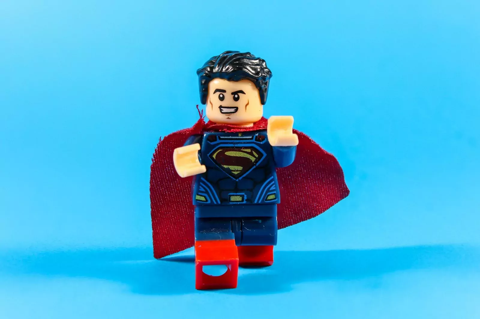 Superman lego figure with red cape on blue background
