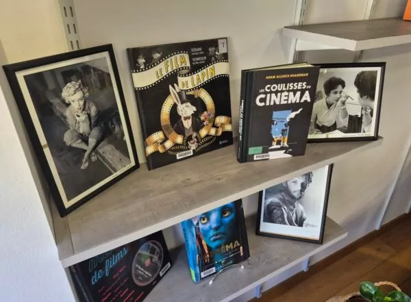 Photos de stars en noir et blanc et livres sur le thème du cinéma disposés sur une étagère.