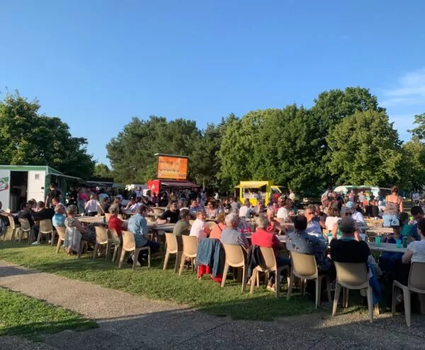 Grandes tablées avec en arrière plan 5 foodtrucks et un grand écran