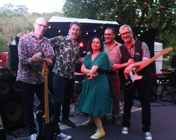 Les 5 artistes du groupe la Boutik Deluxe pose sur la scène avec leurs instruments.