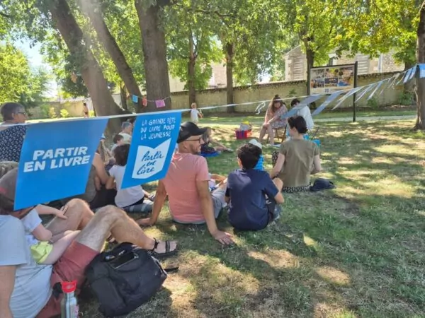 public assis dans l'herbe à l'ombre des ombres du parc du château. une guirlande 