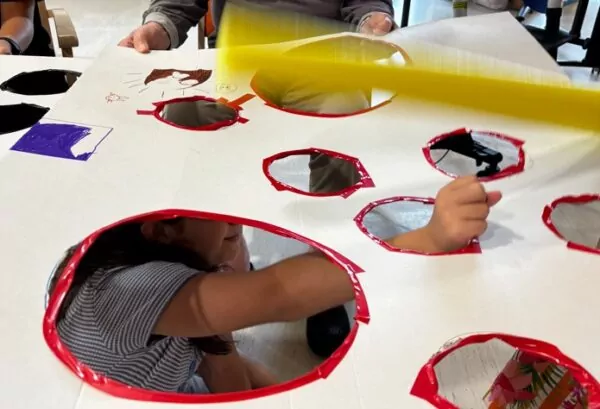 enfant passant sa main dans le trou d'un grand carton