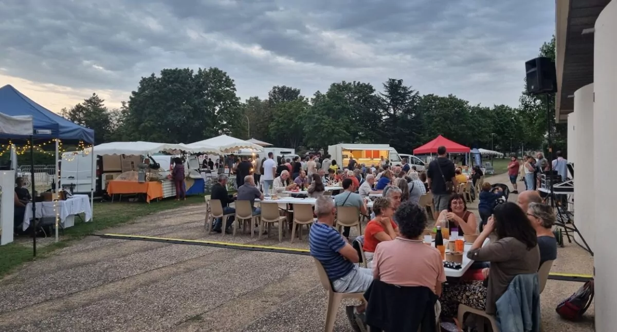 Personnes attablées sur le parvis de l'Agora avec en arrière plan, les stands des producteurs locaux.