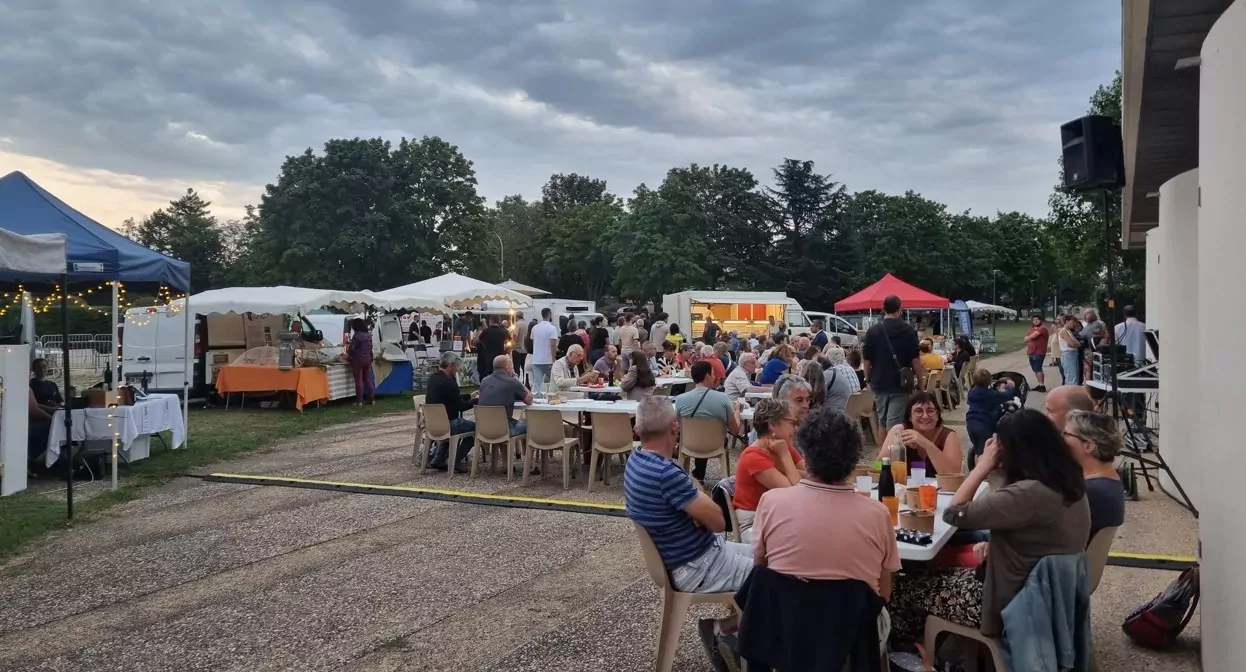 Personnes attablées sur le parvis de l'Agora avec en arrière plan, les stands des producteurs locaux.