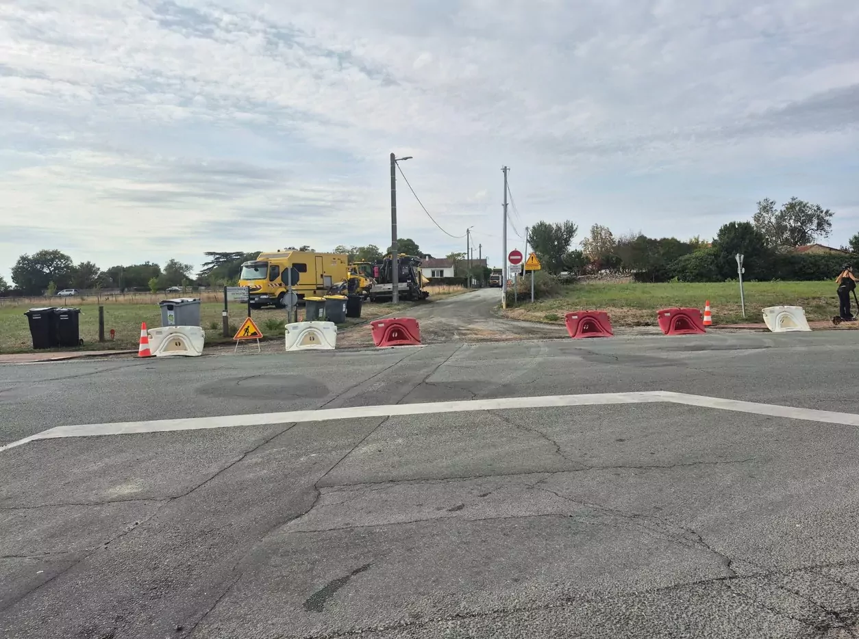 rue de la Haute Payre à Jaunay-Marigny bloquée avec des plots en raison de travaux un tractopelle est stationné sur le côté.