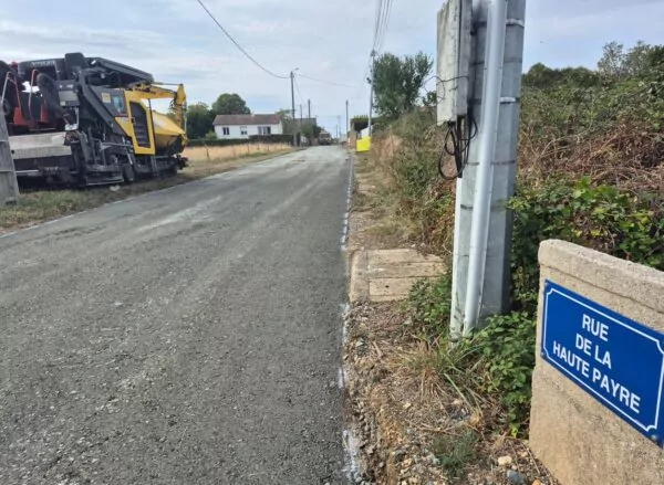 rue en chantier au premier plan le panneau de rue et un engin de travaux publics