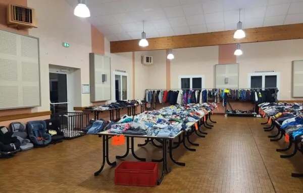 grande tables sur lesquelles sont installés des vêtements triés par taille.