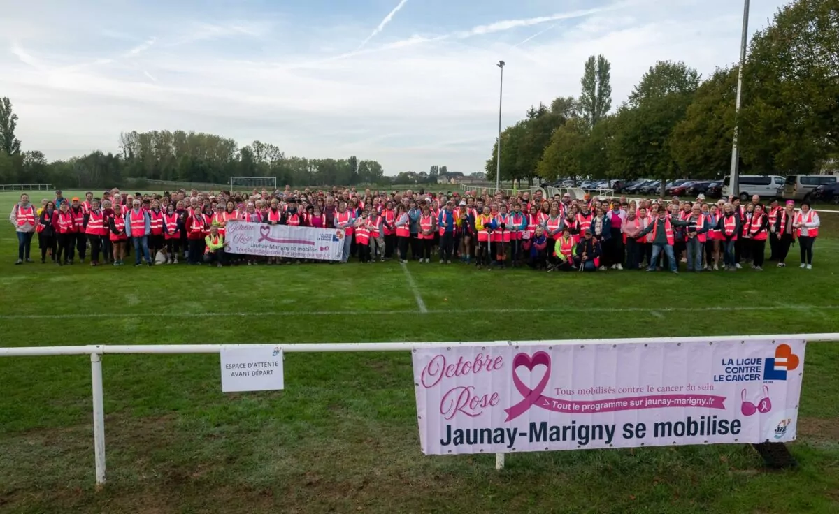 Photo de groupe d'environ 450 personnes portant une chasuble rose sur le stade du complexe sportif Alain Dupleix à Jaunay-Marigny